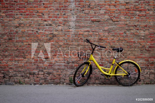 Bild på Yellow Bicycle by the Brick Wall